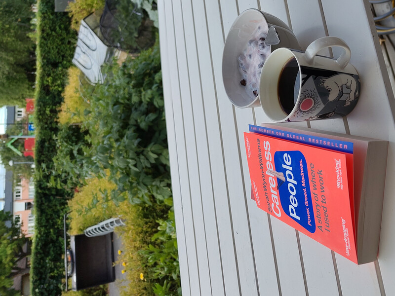 Et utebord med en kaffekopp, en skål kulturmelk og boken 'Careless people'
