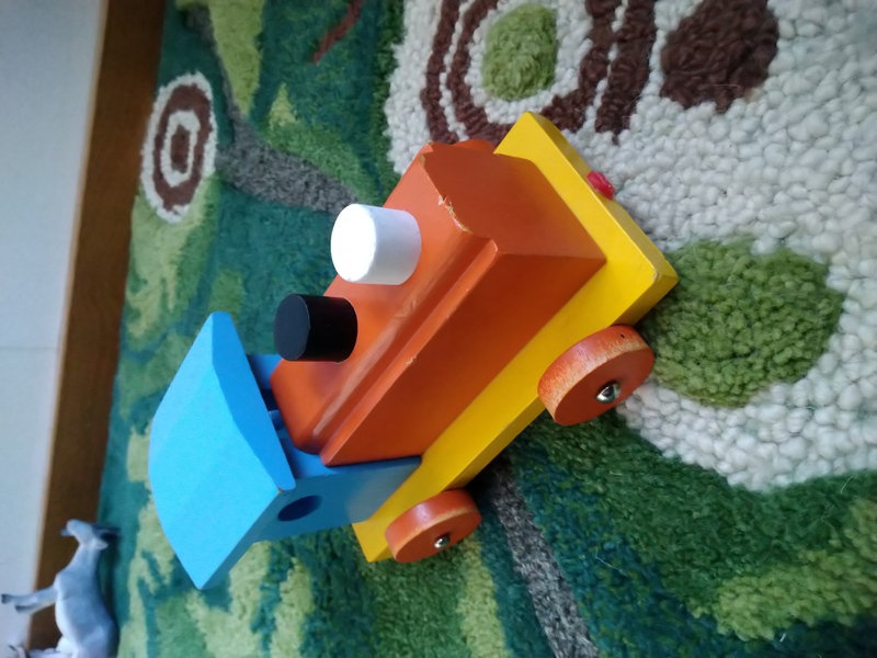 En reparert togleke i tre. Et rødt og blått lokomotiv med en to skorsteiner, en svart og en hvit. Et lekelokomotiv i tre.